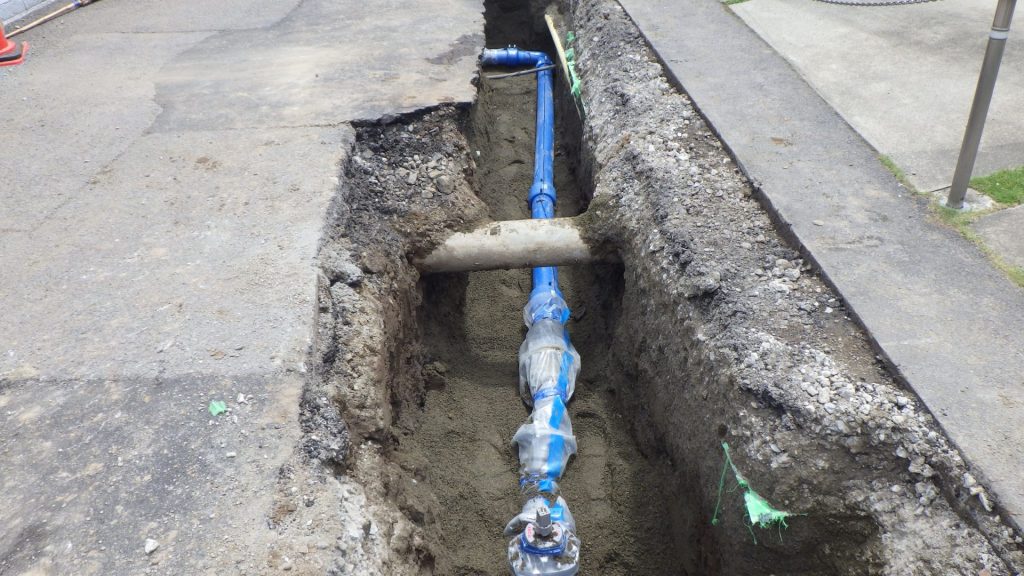 掘削した溝に新しい水道管を設置